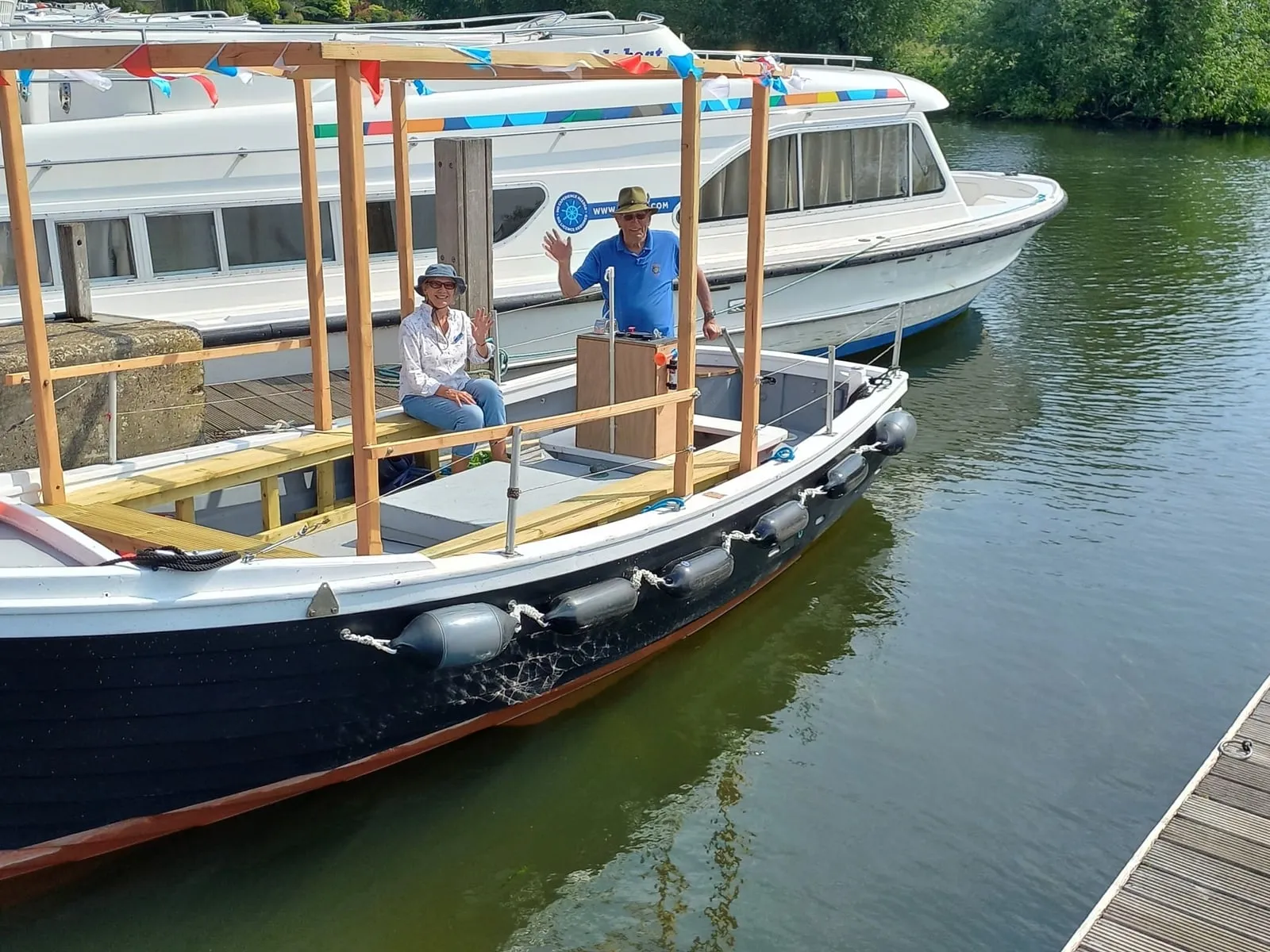 Ferrette on the Thames at Benson with two people aboard, waving